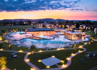 König Ludwig Wellness & Spa Resort Allgäu außenansicht-hotelanlage-mit-pool-in-der-abenddämmerung