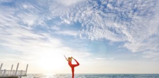 frau-in-roter-sportkleidung-macht-yoga-auf-einem-felsen-am-meer