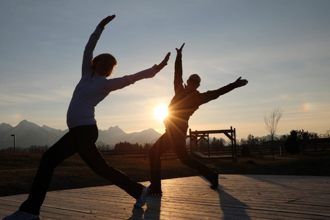 Zwei Personen beim Yoga-Training vor aufgehender Sonne