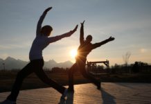 Zwei Personen beim Yoga-Training vor aufgehender Sonne