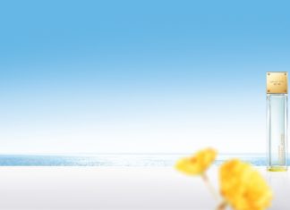 Michael Kors – Die NOBILIS Group wird exklusiver Vertriebspartner Michael Kors Parfum SkyBlossom Bottle Hero mit gelben Blüten vor blauem Hintergrund