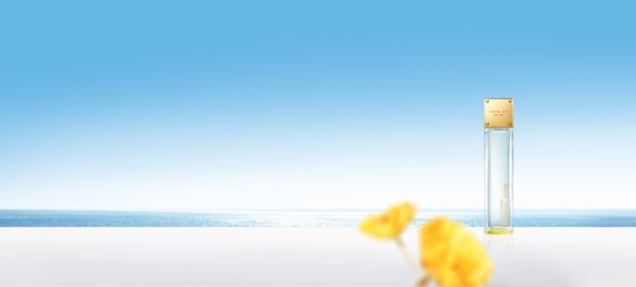 Michael Kors Parfum SkyBlossom Bottle Hero mit gelben Blüten vor blauem Hintergrund