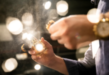 Through The MirrorBlick auf die Esxence 2022 Hände mit Parfumflakon im Scheinwerferlicht