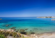 Meeresbucht mit blauem Wasser und badenenden Menschen.