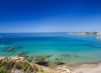 Meeresbucht mit blauem Wasser und badenenden Menschen.