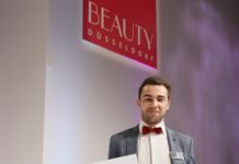 Elias Gharieni hält auf der Beauty Düsseldorf einen großen Scheck in der Hand
