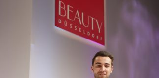 Elias Gharieni hält auf der Beauty Düsseldorf einen großen Scheck in der Hand