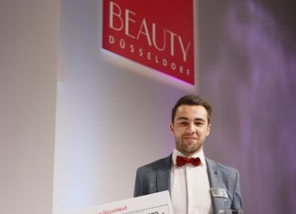 Elias Gharieni hält auf der Beauty Düsseldorf einen großen Scheck in der Hand