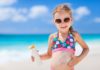 Kleines Mädchen am Meer cremt sich mit Sonnenschutzmittel ein