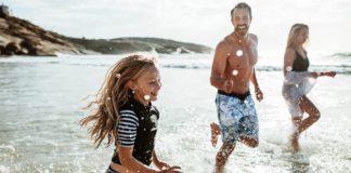 Familie beim Rennen und Spritzen im Wasser am Strand