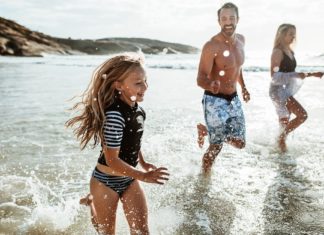 Familie beim Rennen und Spritzen im Wasser am Strand