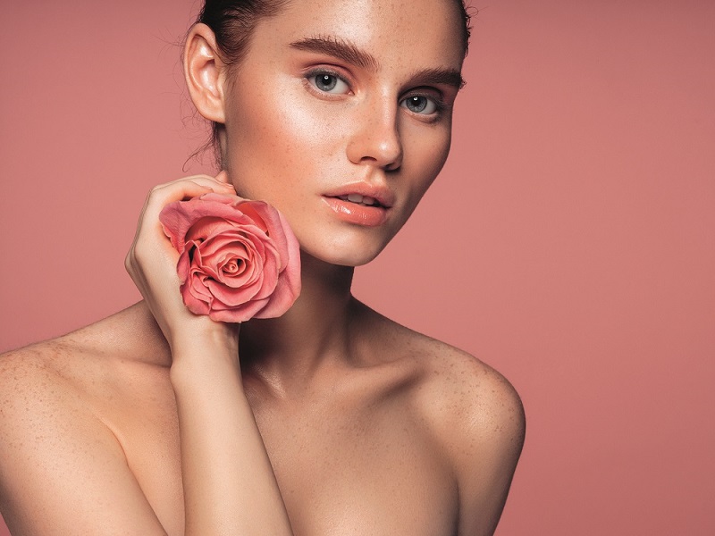 Junge Frau mit Rosenblüte in der Hand