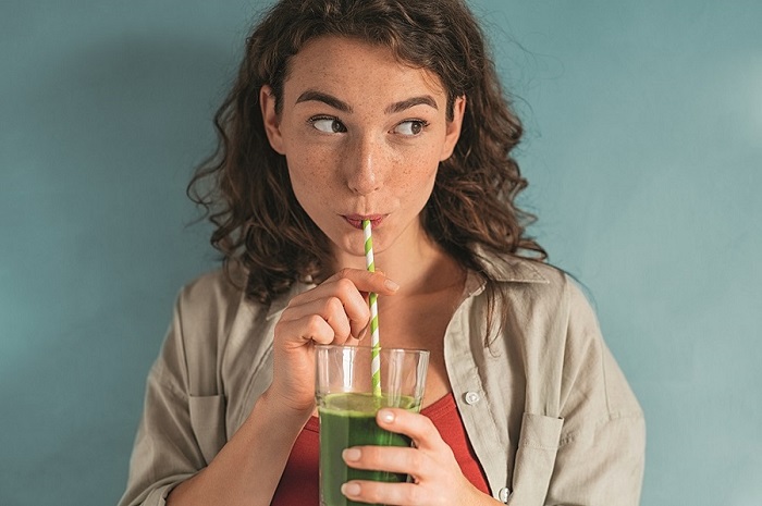 Junge Frau beim Trinken eines grünen Smoothies