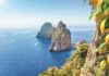 Berühmte Faraglioni-Felsen, Insel Capri, Italien. Schöne paradiesische Landschaft mit azurblauem Meer im sonnigen Sommertag mit reifen gelben Zitronen im Vordergrund