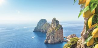 Berühmte Faraglioni-Felsen, Insel Capri, Italien. Schöne paradiesische Landschaft mit azurblauem Meer im sonnigen Sommertag mit reifen gelben Zitronen im Vordergrund