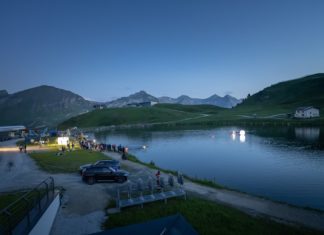 Vollmondschwimmen in traumhafter Alpenkulisse See bei hereinbrechender Dunkelheit und beleuchteter Boje