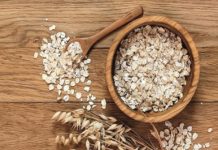 Rolled oats and oat ears of grain on a wooden table, copy space
