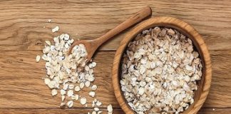 Rolled oats and oat ears of grain on a wooden table, copy space