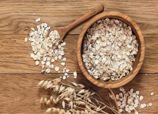 Rolled oats and oat ears of grain on a wooden table, copy space