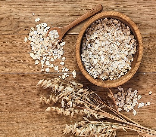 Rolled oats and oat ears of grain on a wooden table, copy space