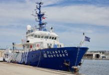 Ein Schiff mit blauem Rumpf und weißem Aufbau liegt im Hafen.
