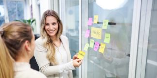 Zwei Frauen stehen vor einer mit Post-Its beklebten Glasfront