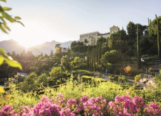 Blühende Gärten im Sonnenschein mit Schloss Trauttmansdorff im Hintergrund