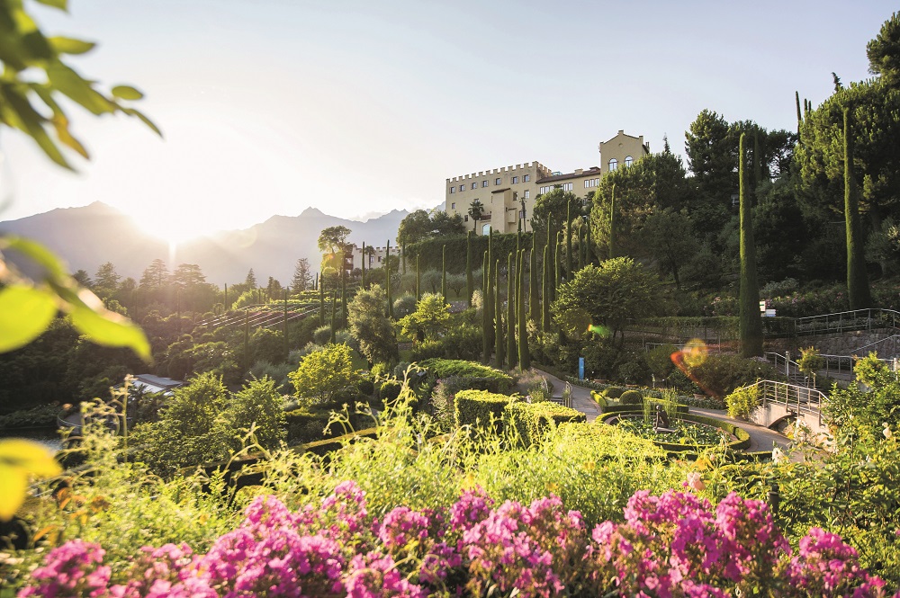 Blühende Gärten im Sonnenschein mit Schloss Trauttmansdorff im Hintergrund
