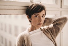 SPA-Insiderin Julia Koschitz Bild von Schauspielerin Julia Koschitz an einen Fensterrahmen lehnend.