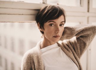 Bild von Schauspielerin Julia Koschitz an einen Fensterrahmen lehnend.