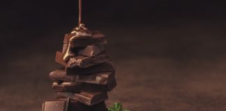 melted chocolate pouring into a piece of chocolate bars with green mint leaf on a table