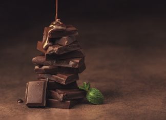 melted chocolate pouring into a piece of chocolate bars with green mint leaf on a table