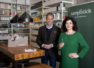 Parfümerie UNIQUE by baslerbeauty gewinnt Ideenwettbewerb Ein Mann und eine Frau im grünen Kleid stehen im Verkaufsraum mit Regalen.