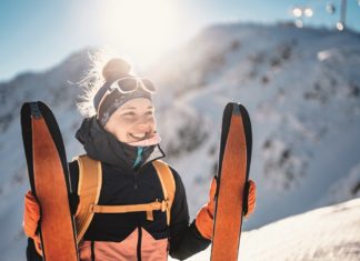 Mountaineer backcountry ski walking ski alpinist in the mountains. Ski touring in alpine landscape with snowy trees. Adventure winter sport.