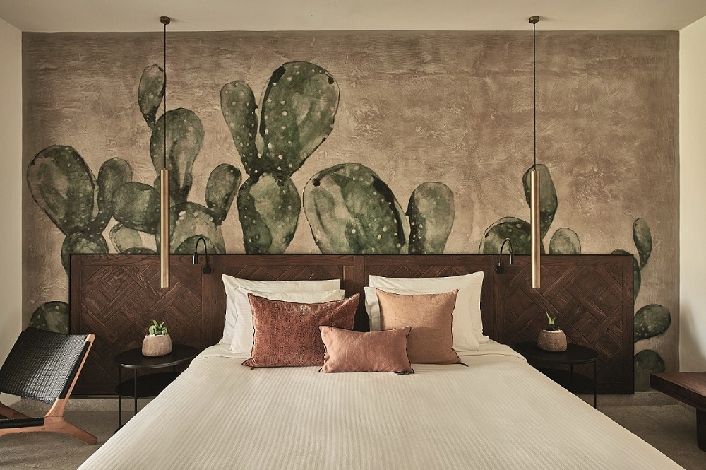 Bett im Hotelzimmer mit einer mit Kakteen bemalten Wand.