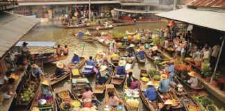 Händler in Holzbooten verkaufen ihre Waren auf einem Fluss-Markt in Bangkok.