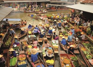 Händler in Holzbooten verkaufen ihre Waren auf einem Fluss-Markt in Bangkok.