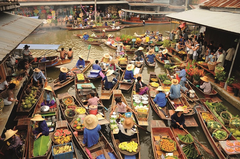 Händler in Holzbooten verkaufen ihre Waren auf einem Fluss-Markt in Bangkok.