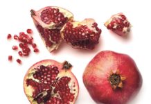 Upcycling Ganzer Granatapfel, aufgeschnittener Granatapfel und Kerne sind auf einem Tisch verteilt.