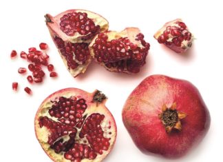 Upcycling Ganzer Granatapfel, aufgeschnittener Granatapfel und Kerne sind auf einem Tisch verteilt.