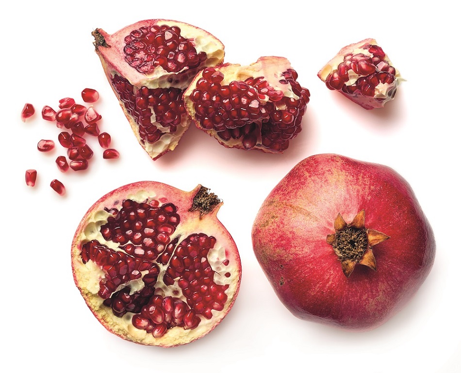 Ganzer Granatapfel, aufgeschnittener Granatapfel und Kerne sind auf einem Tisch verteilt.