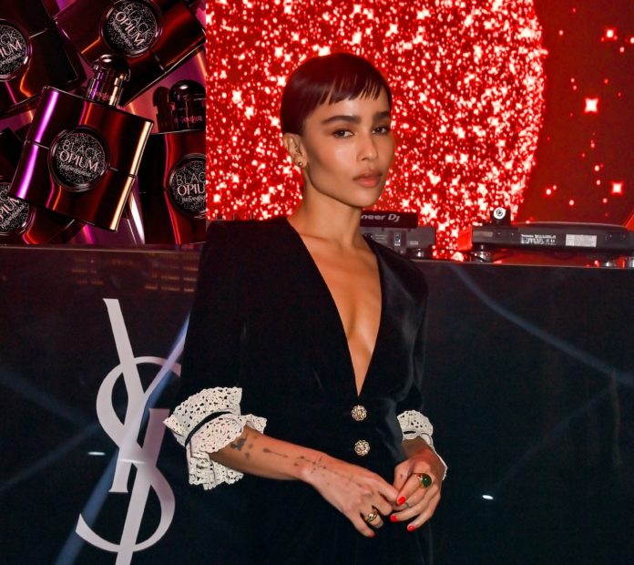 Zoe Krevitz in schwarzer Gala neben YSL-Emblem vor rotem HIntergrund auf der Premierenfeier.