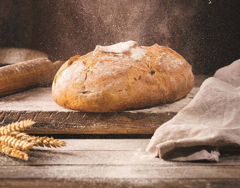 Brotlaib auf mit Mehl bestäubtem Holztisch