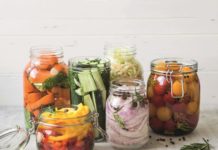 Pickled vegetables. Salting various vegetables in glass jars for long-term storage. Preserves vegetables in glass jars. Variety fermented green vegetables on table.