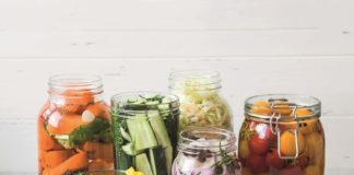 Pickled vegetables. Salting various vegetables in glass jars for long-term storage. Preserves vegetables in glass jars. Variety fermented green vegetables on table.