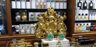 Ladentheke einer Parfümerie mit vielen unterschiedlichen Flakons und einem goldenen Wappen im Hintergrund.
