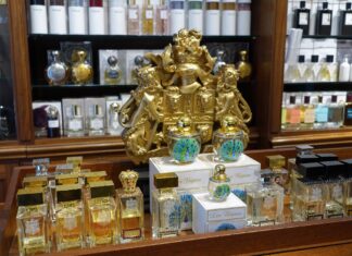 Eintauchen in eine Welt aus 1000 Düften Ladentheke einer Parfümerie mit vielen unterschiedlichen Flakons und einem goldenen Wappen im Hintergrund.