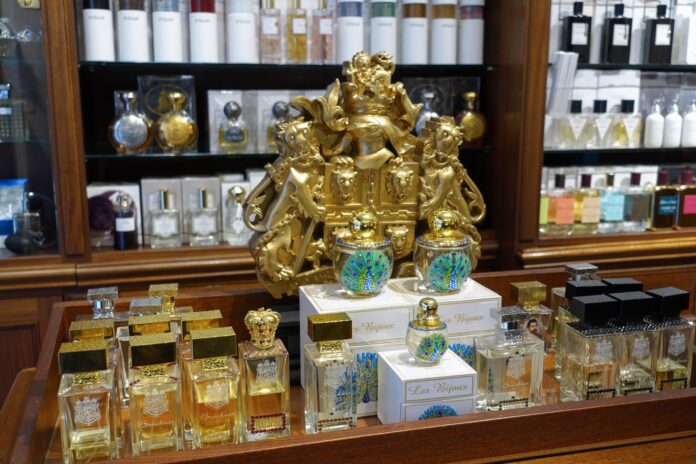 Ladentheke einer Parfümerie mit vielen unterschiedlichen Flakons und einem goldenen Wappen im Hintergrund.