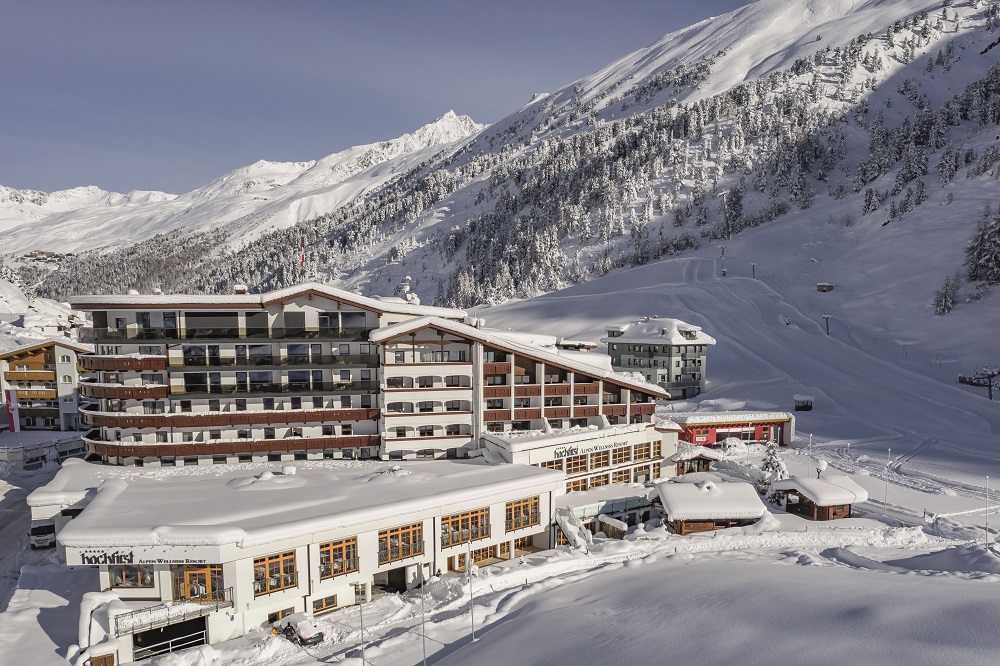Hotelgebäude mit Hütten inmitten eines verschneiten Alpentals