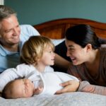 Eine Familie mit zwei kleinen Kindern kuschelt in einem großen Bett
